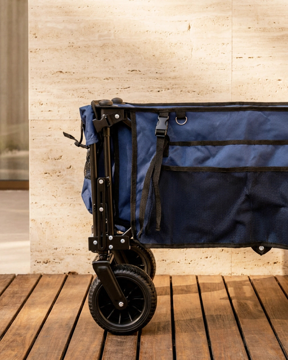 Close-up view of the reinforced black steel frame and 360-degree swivel wheels of the 180L foldable utility cart on a wooden patio.