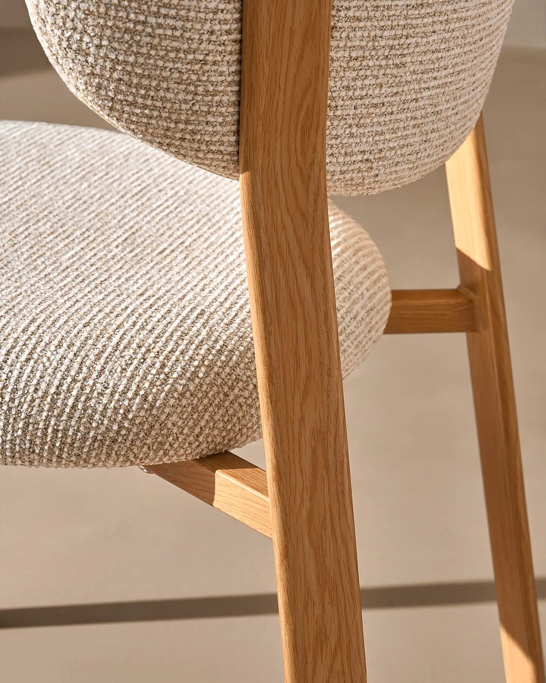 Close-up of the warm wood-effect chair leg and textured cream chenille upholstery on the Bramley dining chair