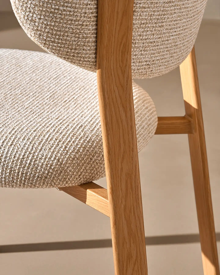 Close-up of the warm wood-effect chair leg and textured cream chenille upholstery on the Bramley dining chair