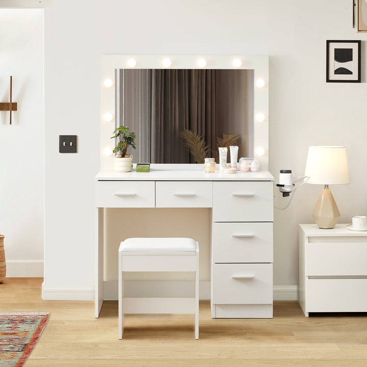 A 5-drawer Hollywood White Dressing Table with a stool, a large mirror, 10 bulbs, and a hairdryer holder in a bright bedroom