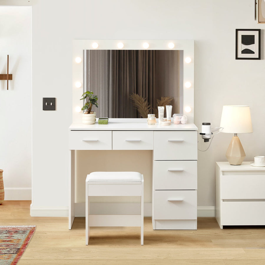 A 5-drawer Hollywood White Dressing Table with a stool, a large mirror, 10 bulbs, and a hairdryer holder in a bright bedroom