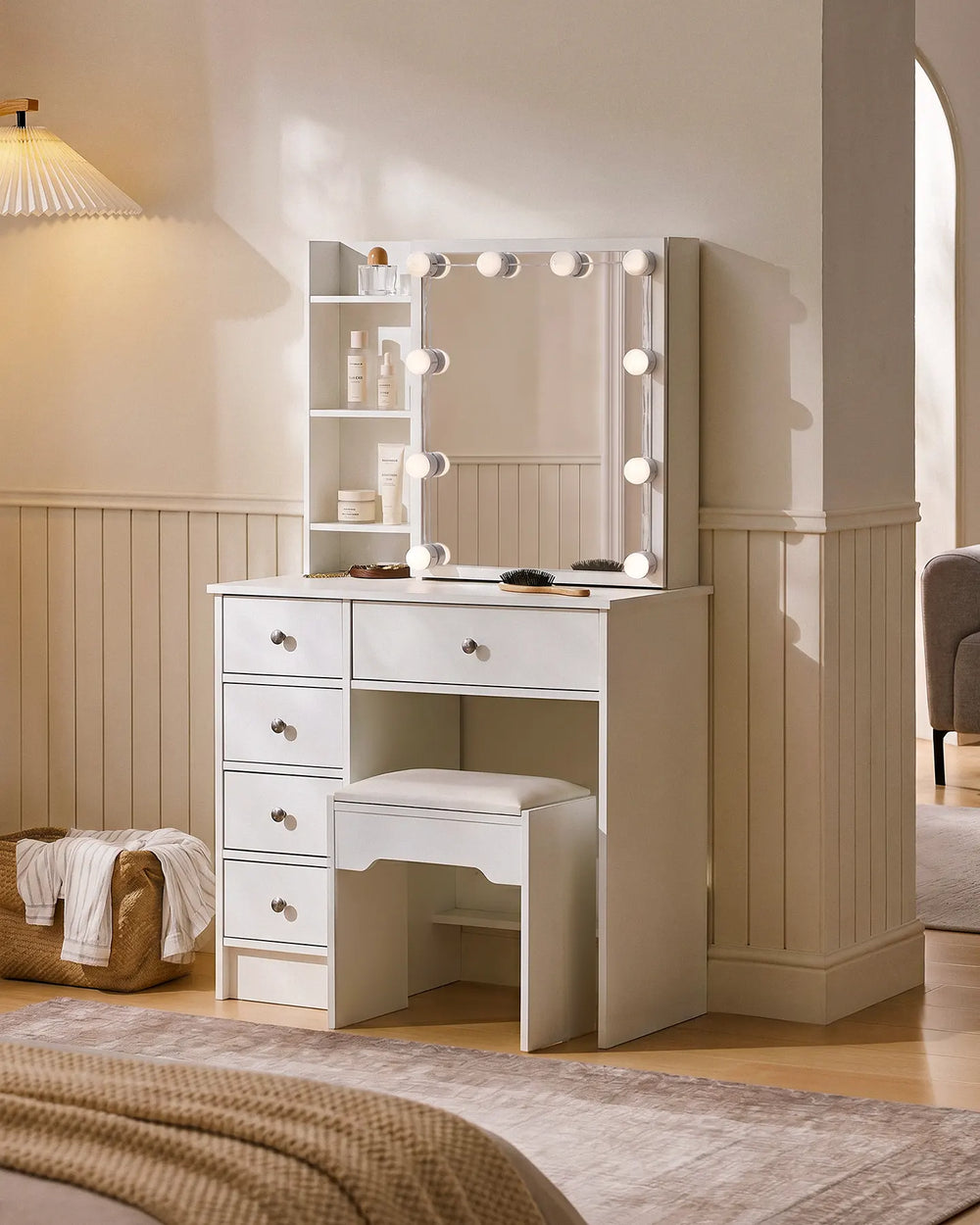 Angled view of a white dressing table with mirror, Hollywood LED bulbs, open shelving, five drawers and matching vanity stool