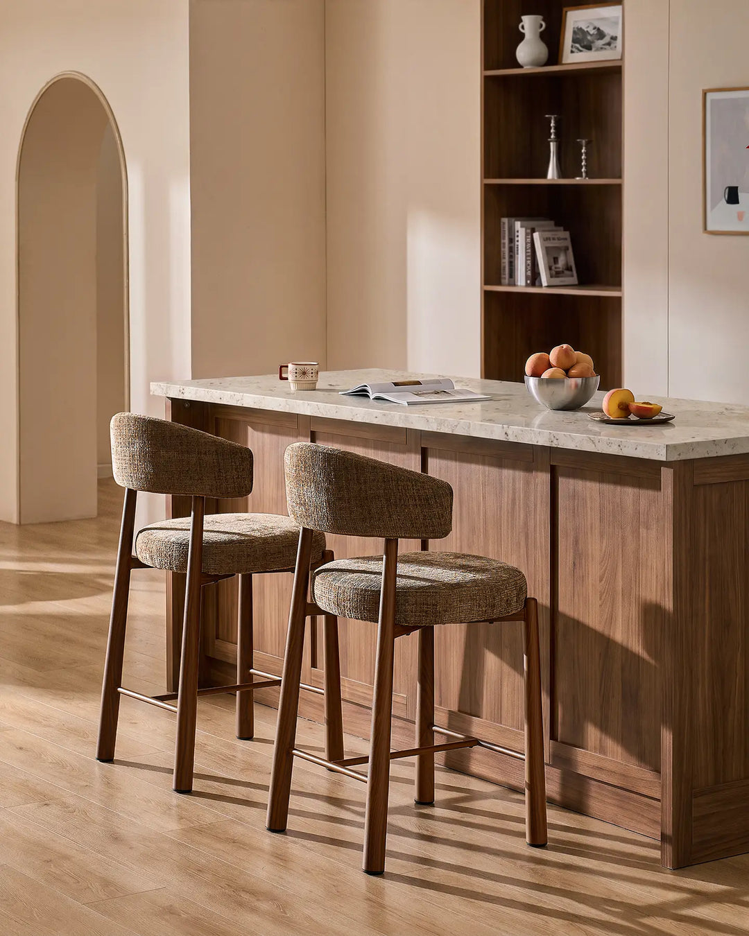 Two Ansel mocha brown chenille breakfast bar stools with wood-effect metal legs styled at a kitchen island with neutral terrazzo countertop and warm interior decor