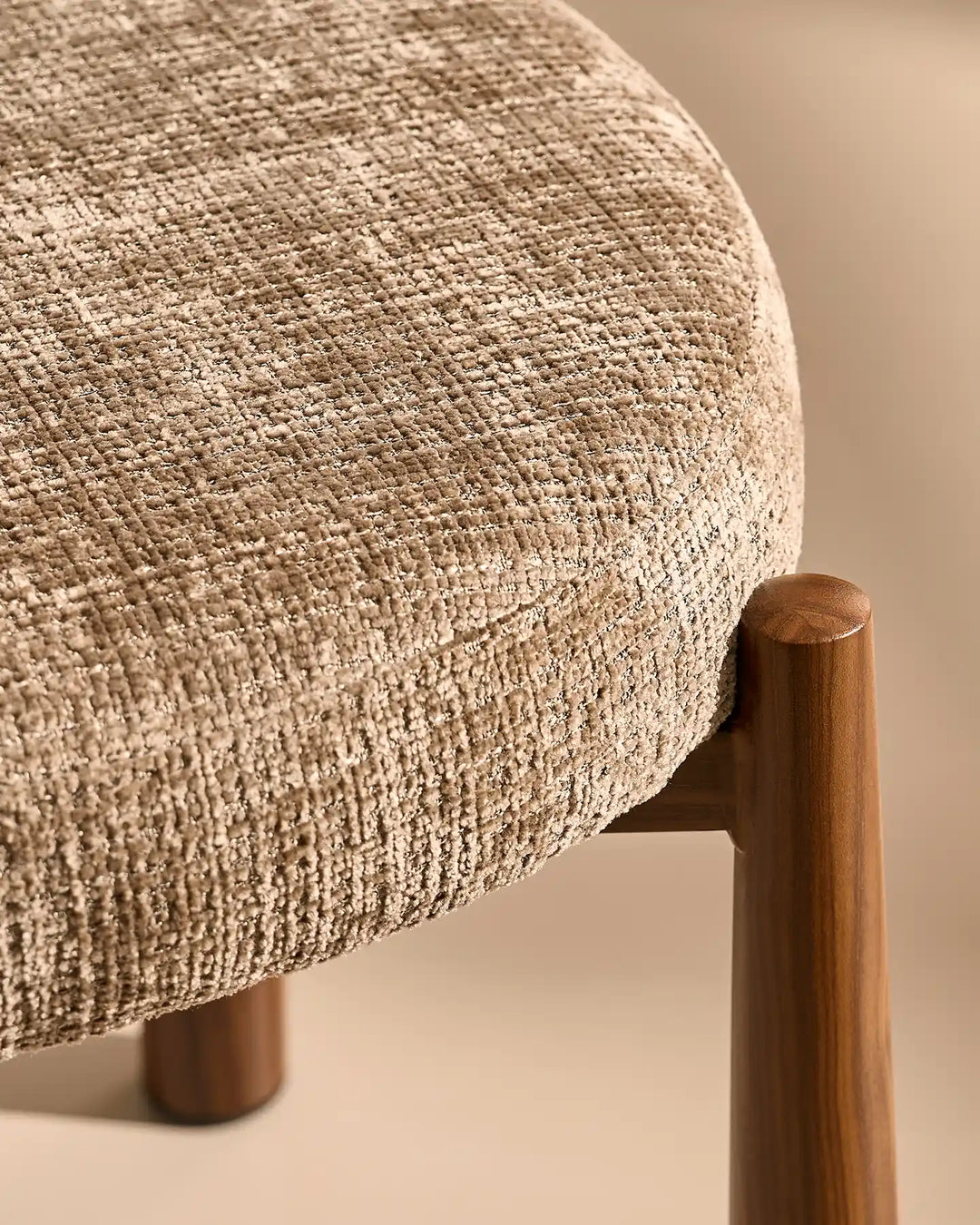 Close-up of the Ansel Mocha Chenille Dining Chair showing the connection between the upholstered seat and its tapered wooden-effect leg.