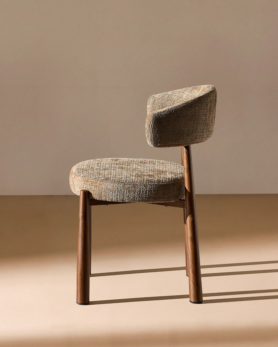 Side profile of the Ansel Mocha Chenille Dining Chair highlighting its curved backrest, upholstered seat and angled legs.