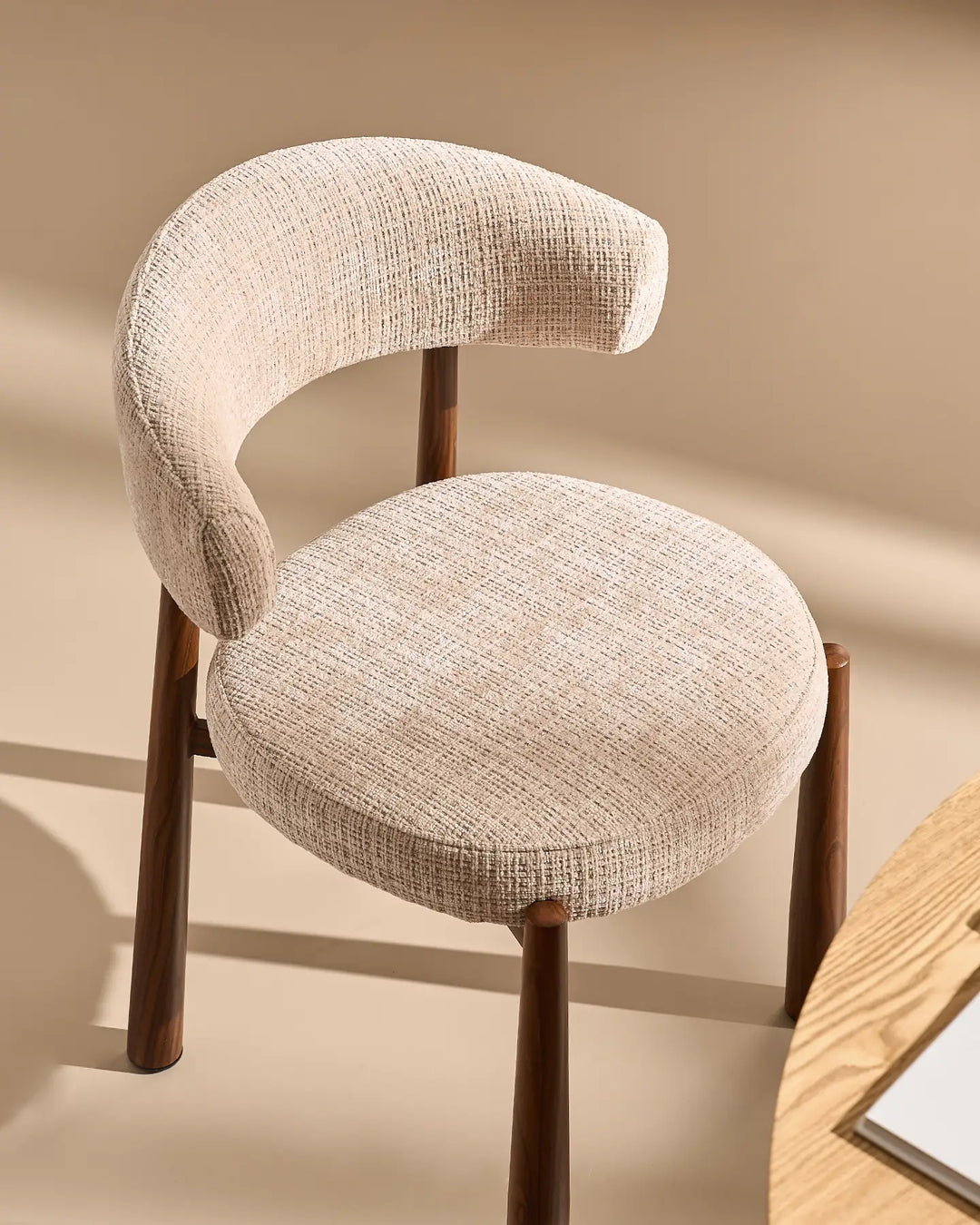 Angled view of the Ansel Oatmeal Chenille Dining Chair showcasing its sculptural backrest, textured mocha chenille fabric and wooden-effect legs.