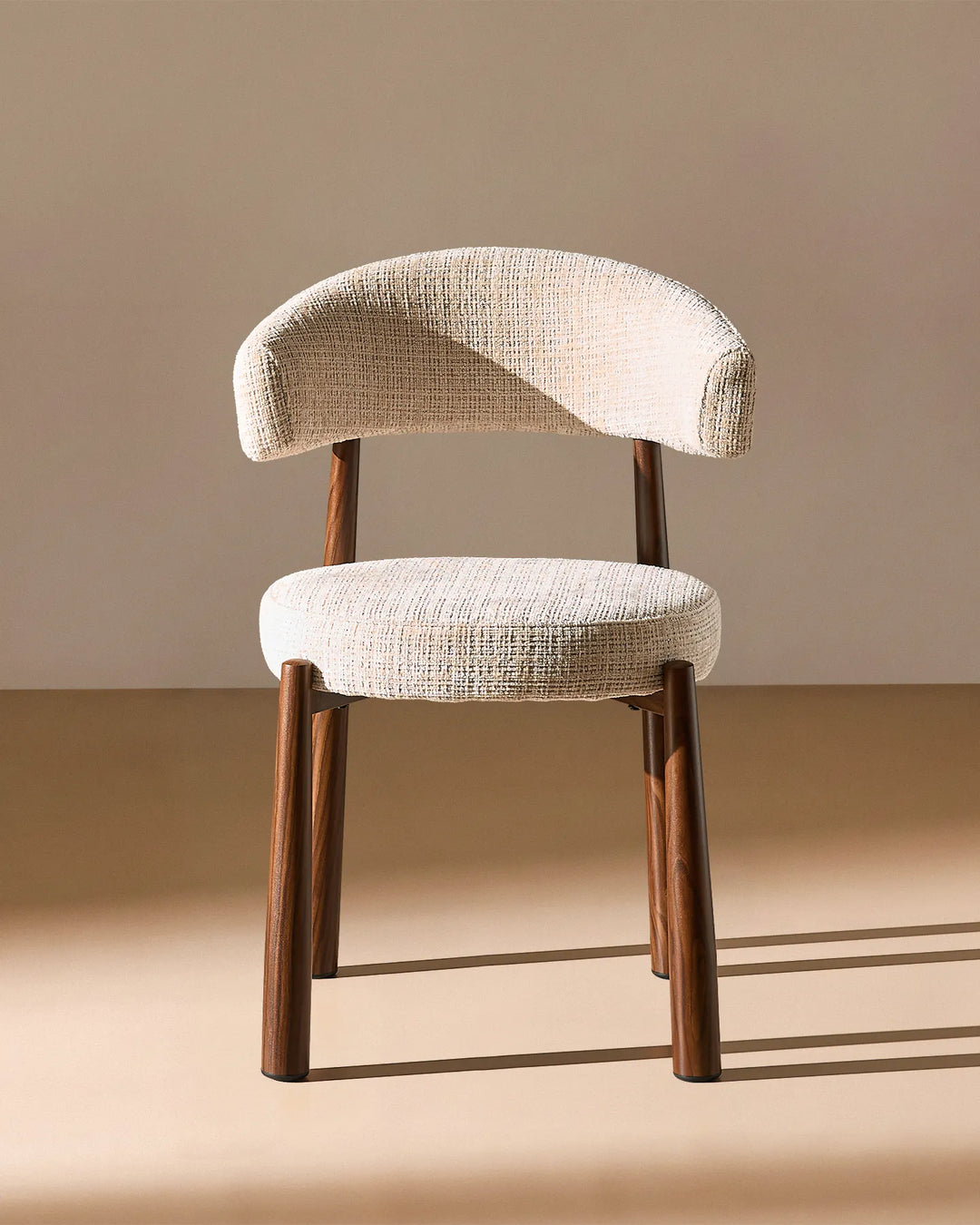 Front view of the Ansel Oatmeal Chenille Dining Chair showing its curved upholstered backrest, rounded seat and slim wooden-effect legs.