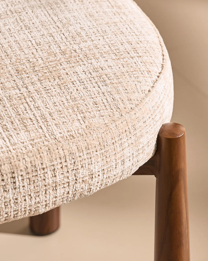 Close-up of the Ansel Oatmeal Chenille Dining Chair showing the connection between the upholstered seat and its tapered wooden-effect leg.