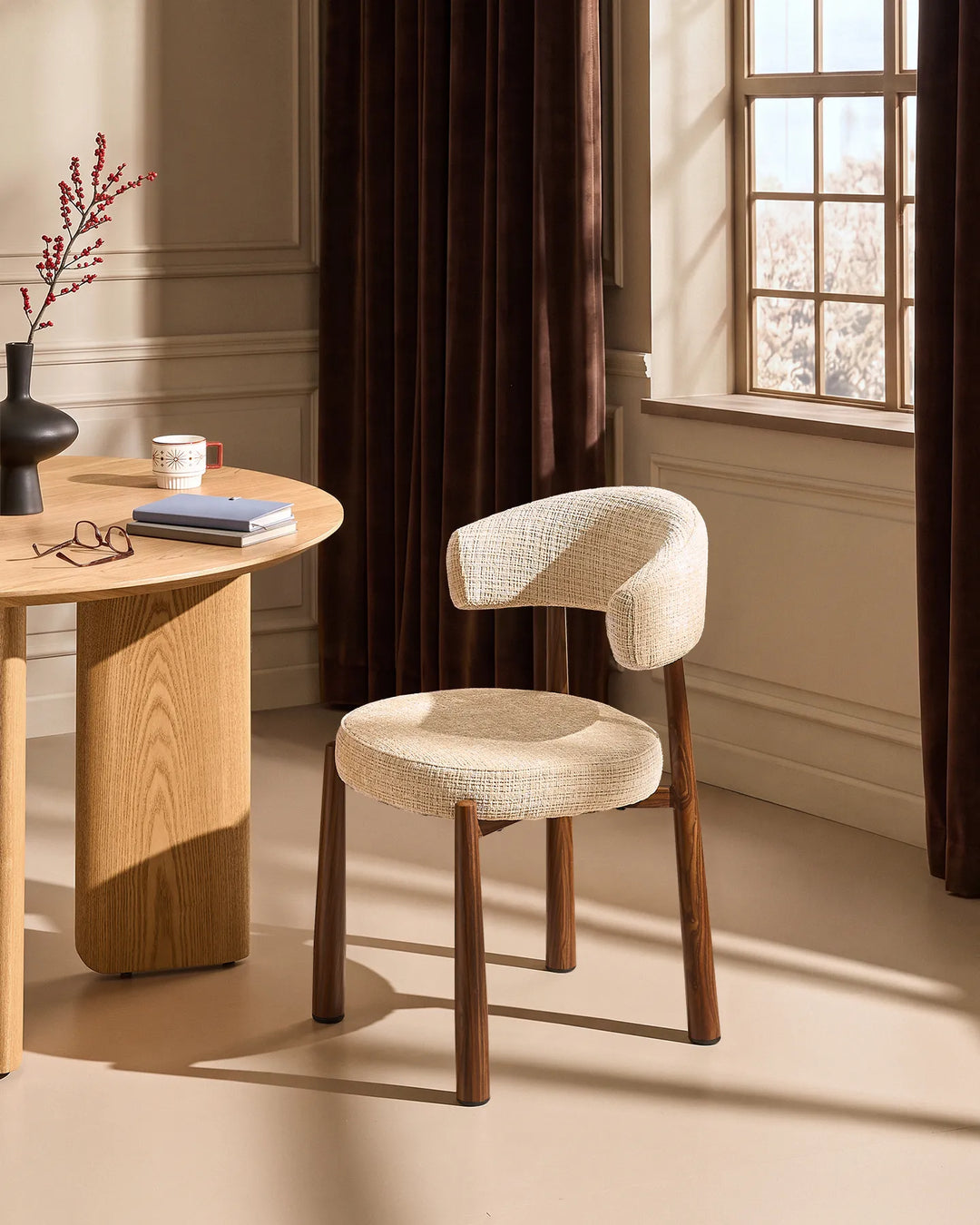 Ansel Oatmeal Chenille Dining Chair with curved upholstered backrest and wooden-effect legs beside a light oak dining table in a warm neutral dining room.