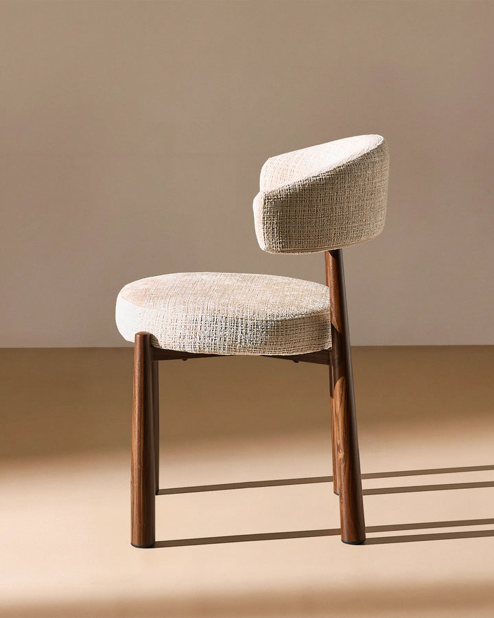Side profile of the Ansel Oatmeal Chenille Dining Chair highlighting its curved backrest, upholstered seat and angled legs.