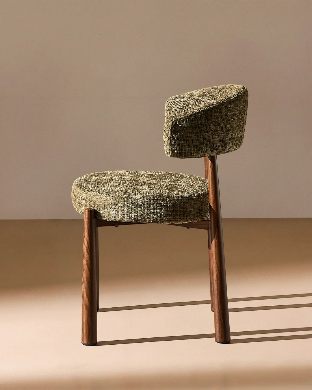 Side profile of the Ansel Olive Green Chenille Dining Chair highlighting its curved backrest, upholstered seat and angled legs.