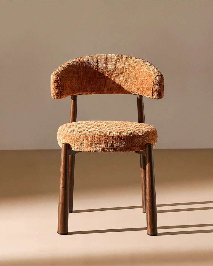 Front view of the Ansel Terracotta Chenille Dining Chair showing its curved upholstered backrest, rounded seat and slim wooden-effect legs.