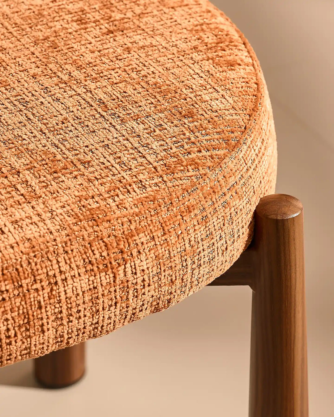 Close-up of the Ansel Terracotta Chenille Dining Chair showing the connection between the upholstered seat and its tapered wooden-effect leg.