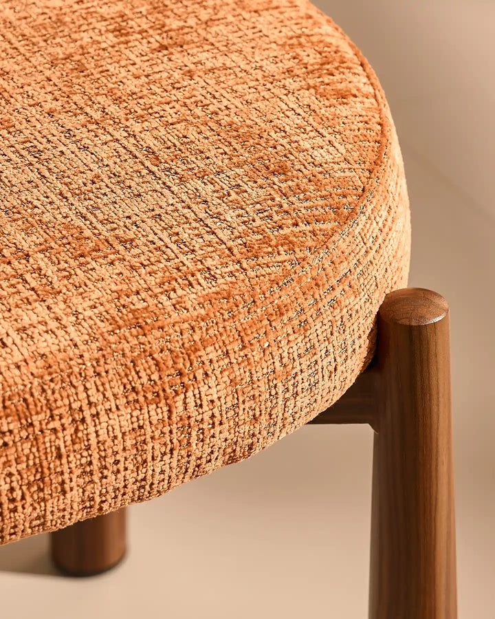Close-up of the Ansel Terracotta Chenille Dining Chair showing the connection between the upholstered seat and its tapered wooden-effect leg.