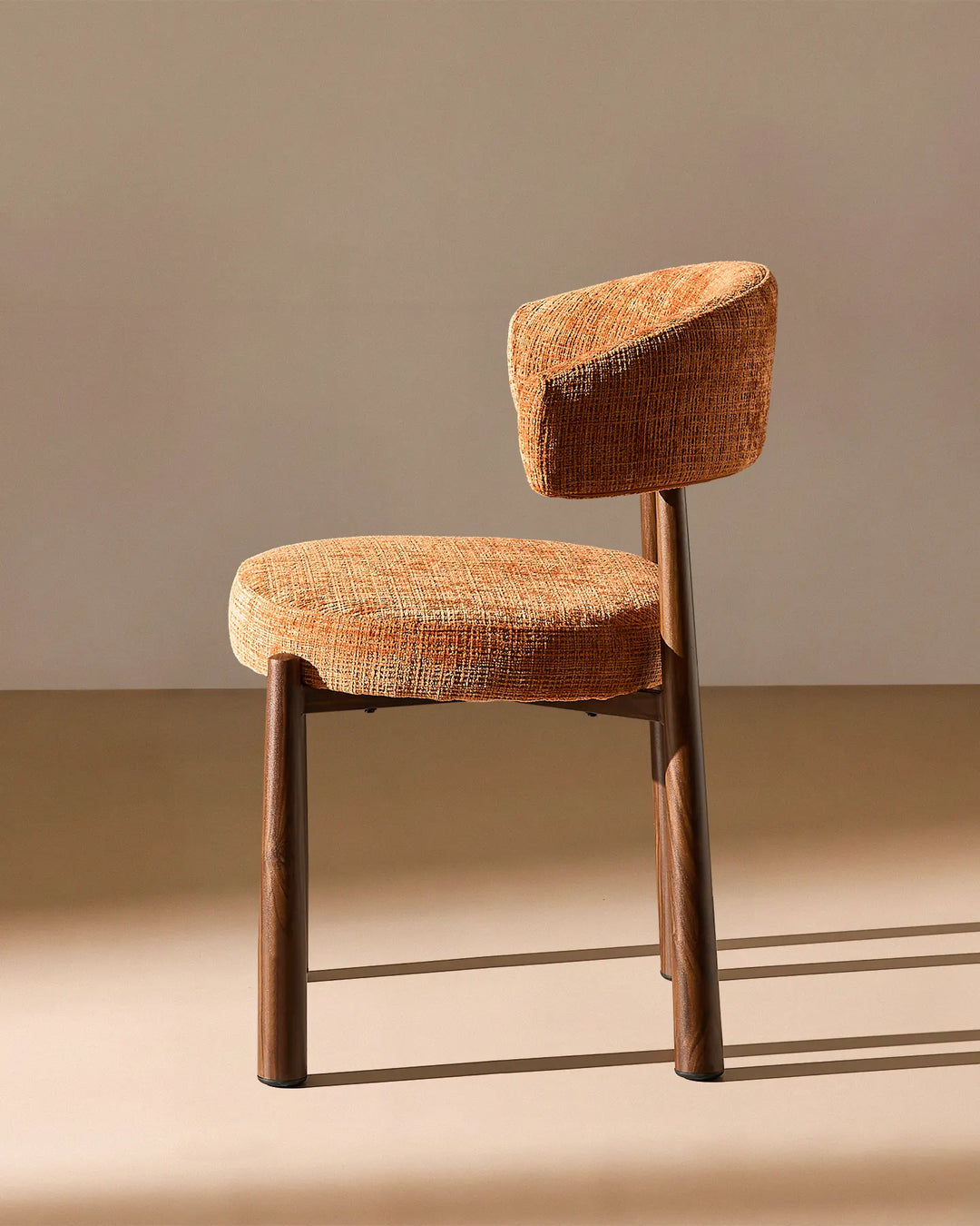 Side profile of the Ansel Terracotta Chenille Dining Chair highlighting its curved backrest, upholstered seat and angled legs.