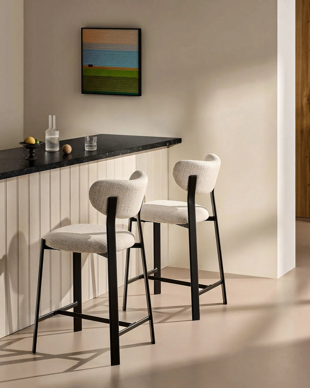 Side view of two Bramley Black Oak Bar Stools beside a kitchen island in a modern rustic interior