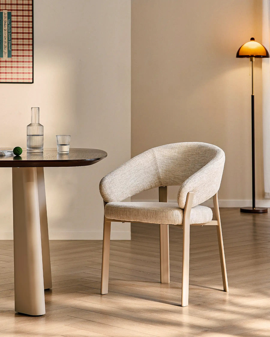 Bramley ivory and off white upholstered dining armchair beside a rustic dining table in a relaxed farmhouse interior