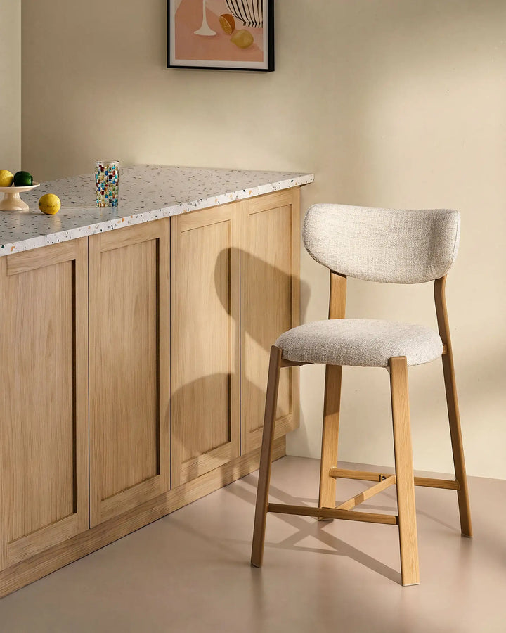 Bramley Oak Bar Stool beside a kitchen island with linen fabric upholstery and wood effect legs, modern farmhouse seating