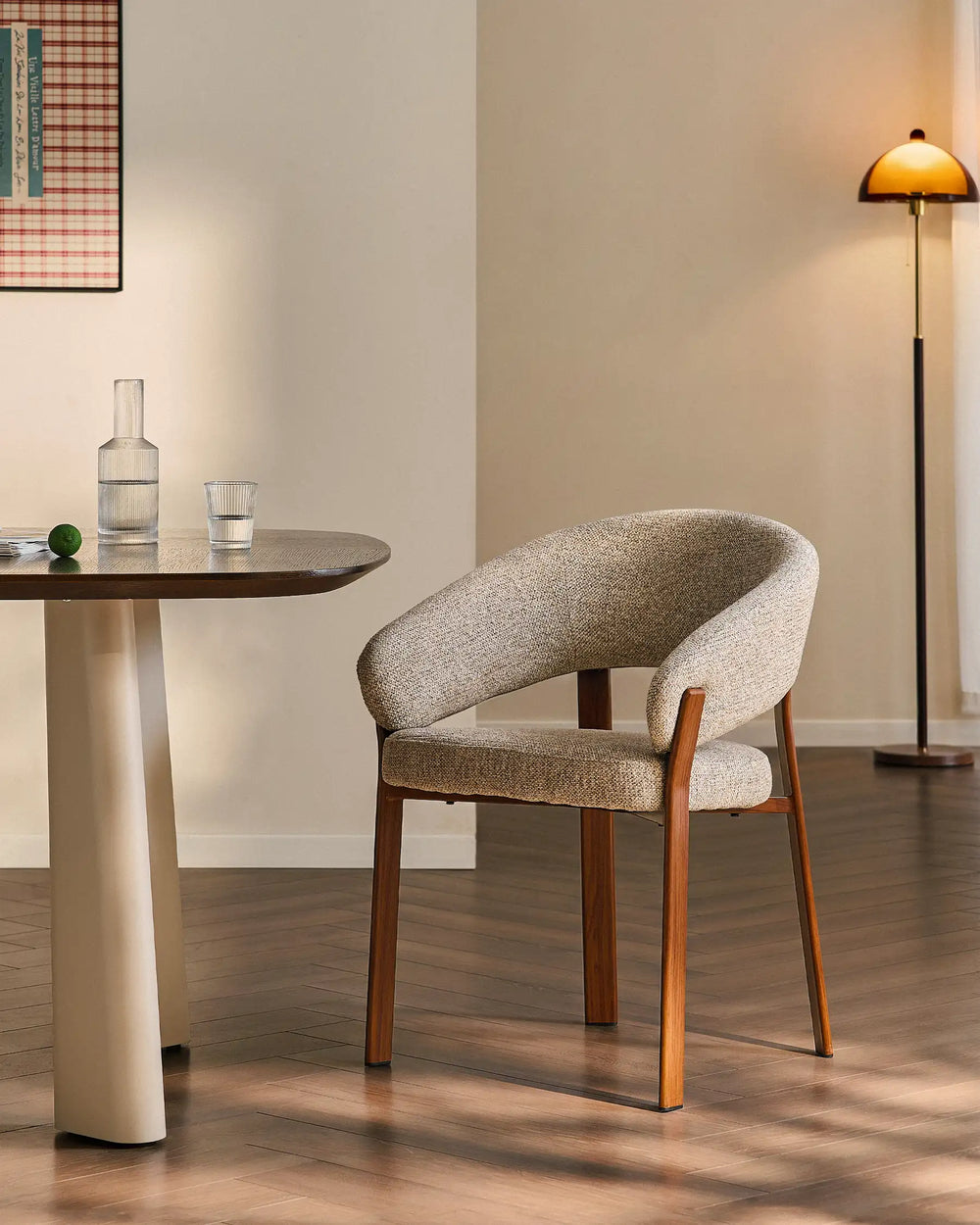 Bramley warm taupe and walnut upholstered dining armchair beside a rustic dining table in a relaxed farmhouse interior