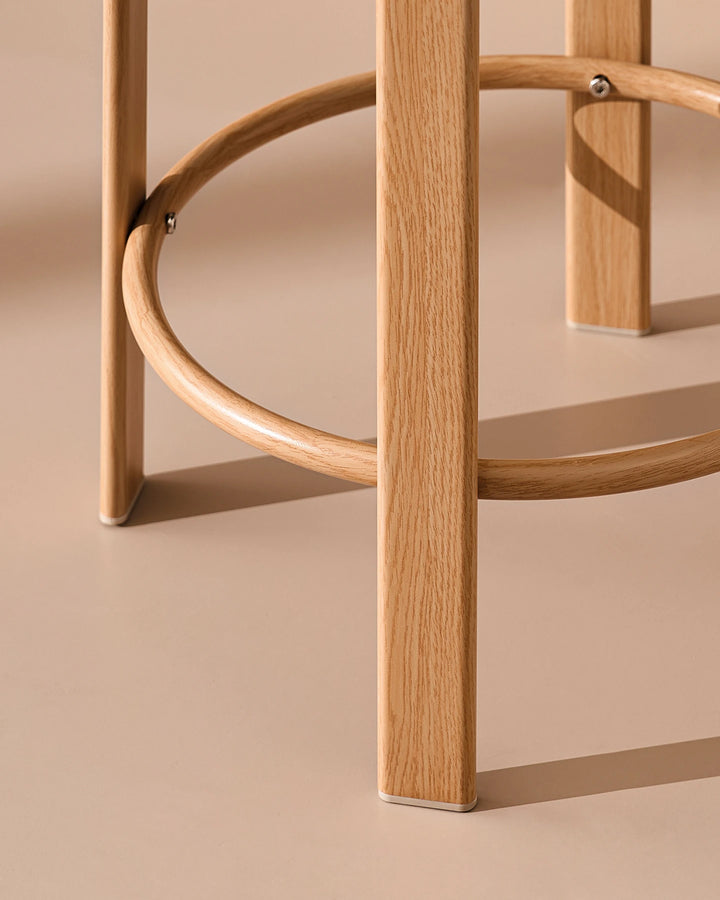 Close-up of the Bramley bar stool frame and circular footrest, showing the curved metal support and oak-effect veneer finish