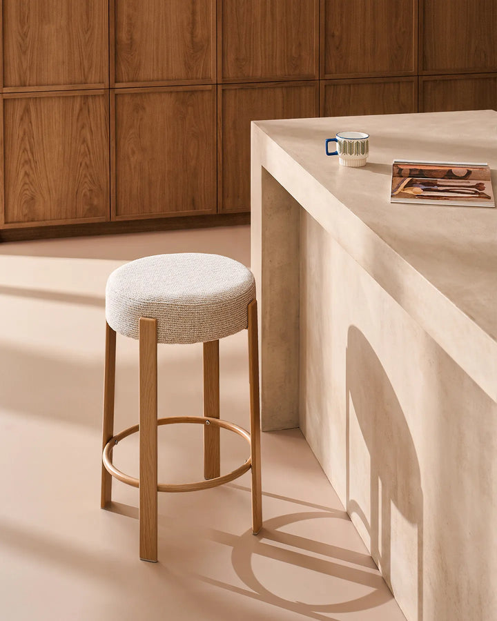 Bramley cream chenille backless bar stool styled beside a kitchen island, featuring a softly rounded seat, wood-effect veneer frame and circular footrest