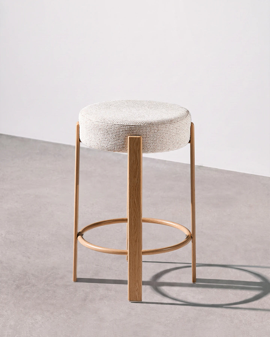Bramley cream chenille backless bar stool shown from the side, highlighting its slim profile, rounded seat and wood-effect veneer frame