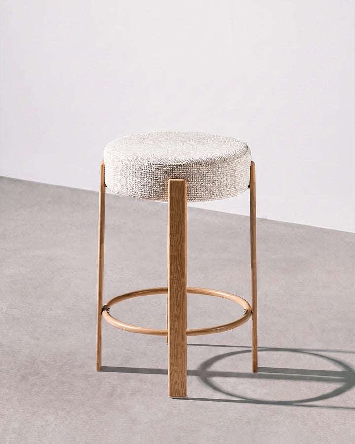 Bramley cream chenille backless bar stool shown from the side, highlighting its slim profile, rounded seat and wood-effect veneer frame