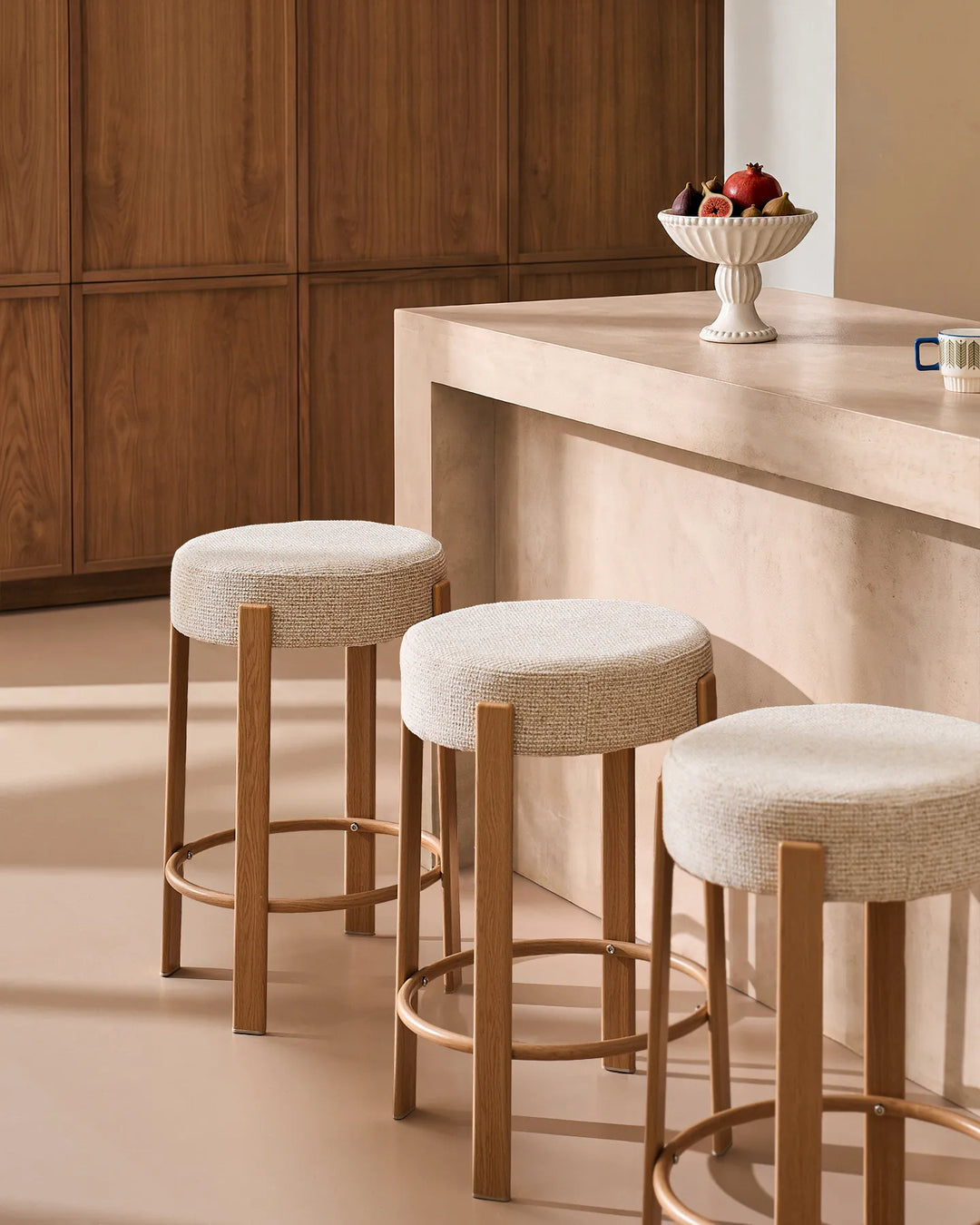 Three Bramley cream chenille backless bar stools arranged along a kitchen island, highlighting the matching design, rounded seats and slim frames