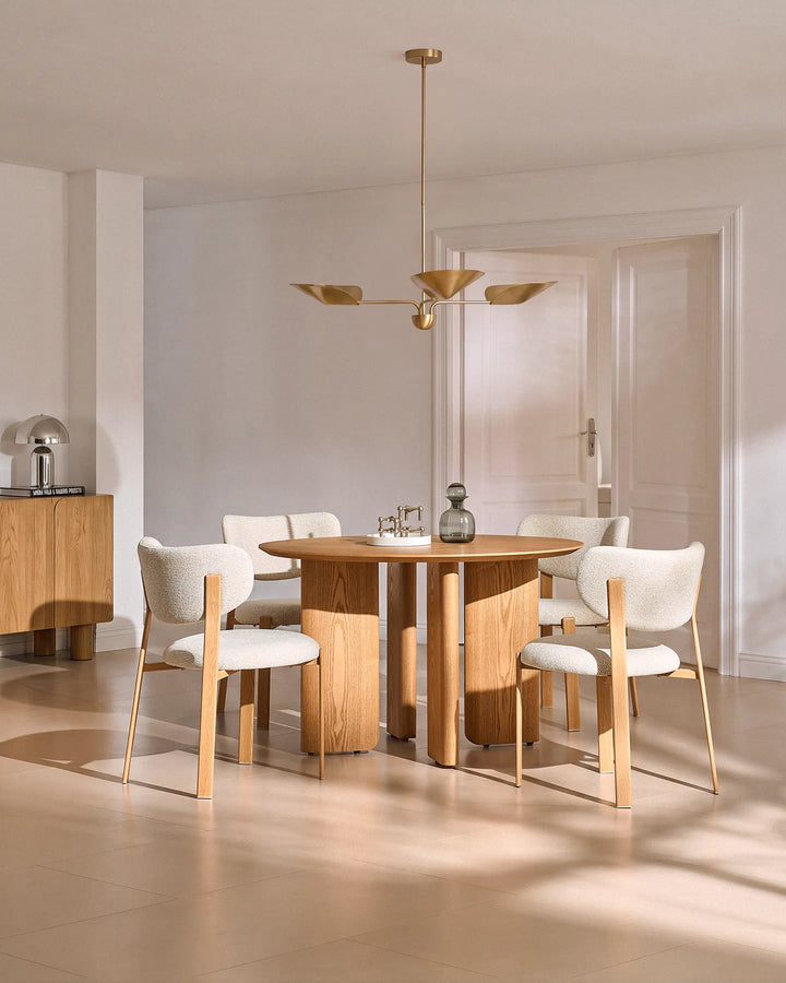 Cream chenille dining chairs paired with a round wooden dining table in a contemporary dining space with natural light