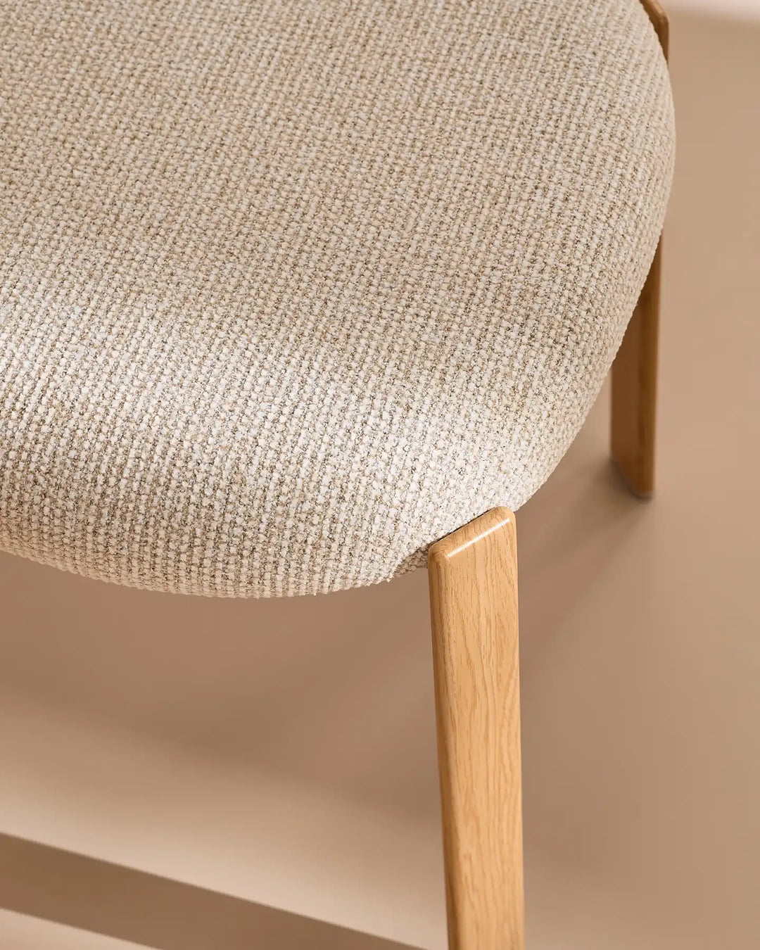 Detailed view of the textured cream chenille upholstery and wood-effect legs of the Bramley dining chair