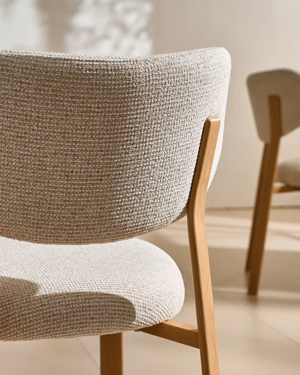 Close-up of the textured cream chenille fabric on the curved backrest and seat of the Bramley dining chair