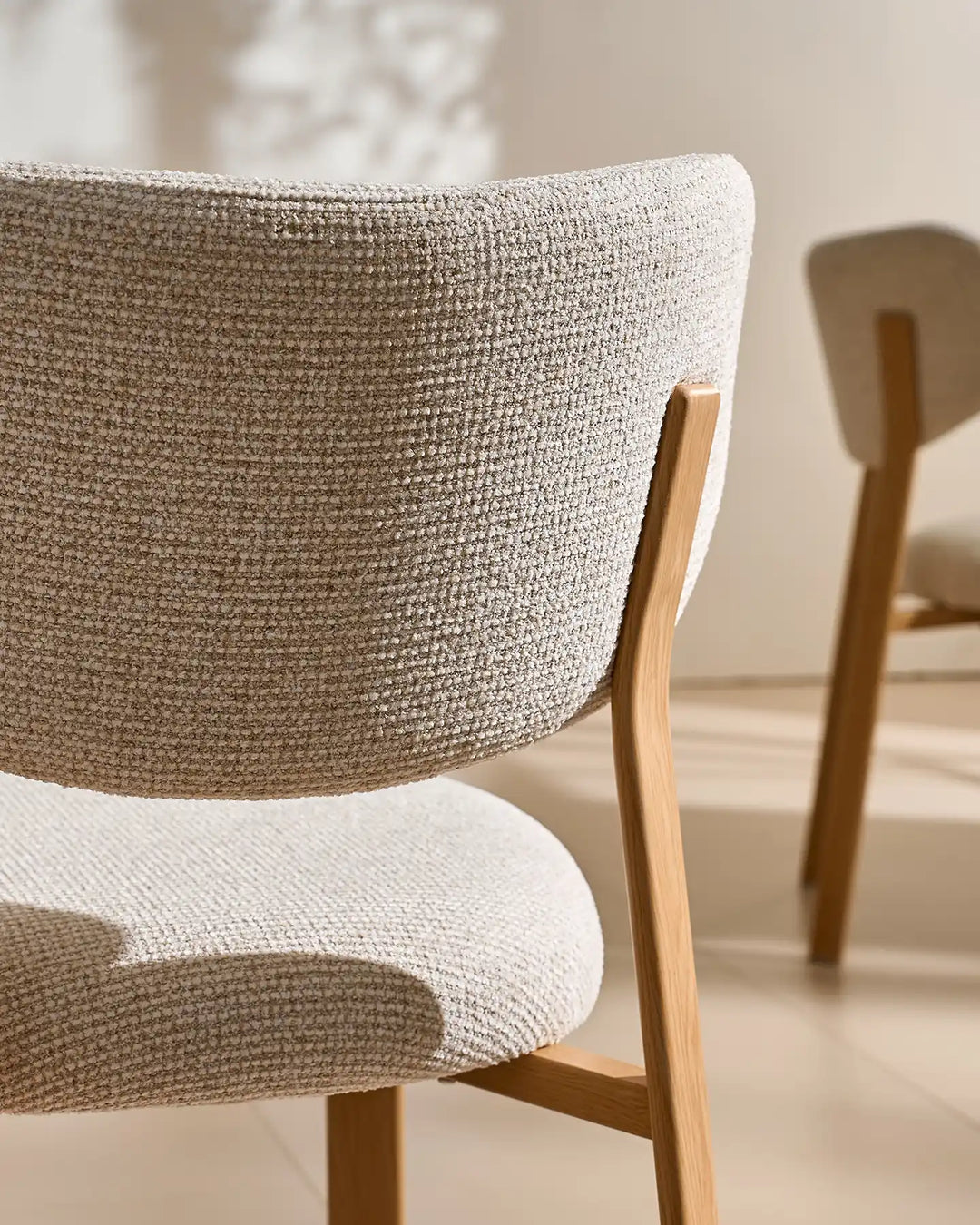 Close-up of the textured cream chenille fabric on the curved backrest and seat of the Bramley dining chair