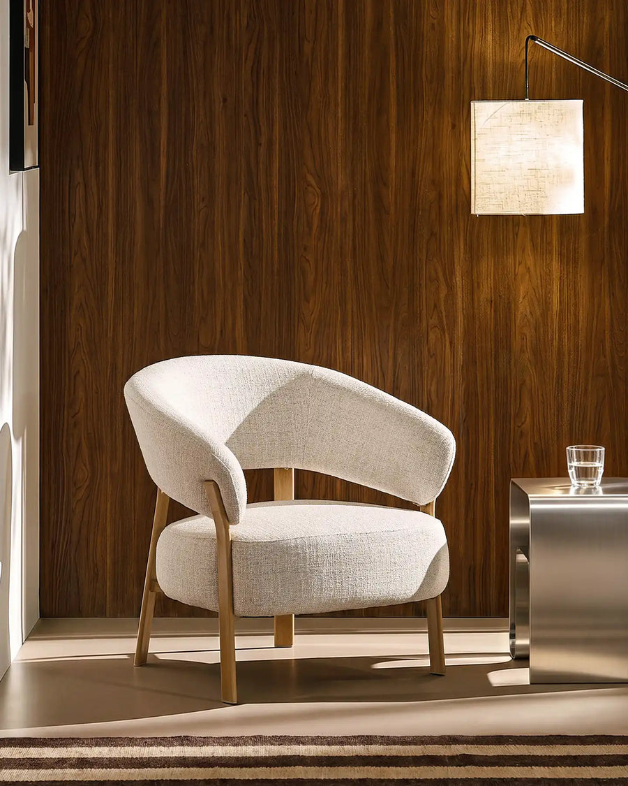 Cream linen upholstered accent chair in a modern living room with dark wood panelling