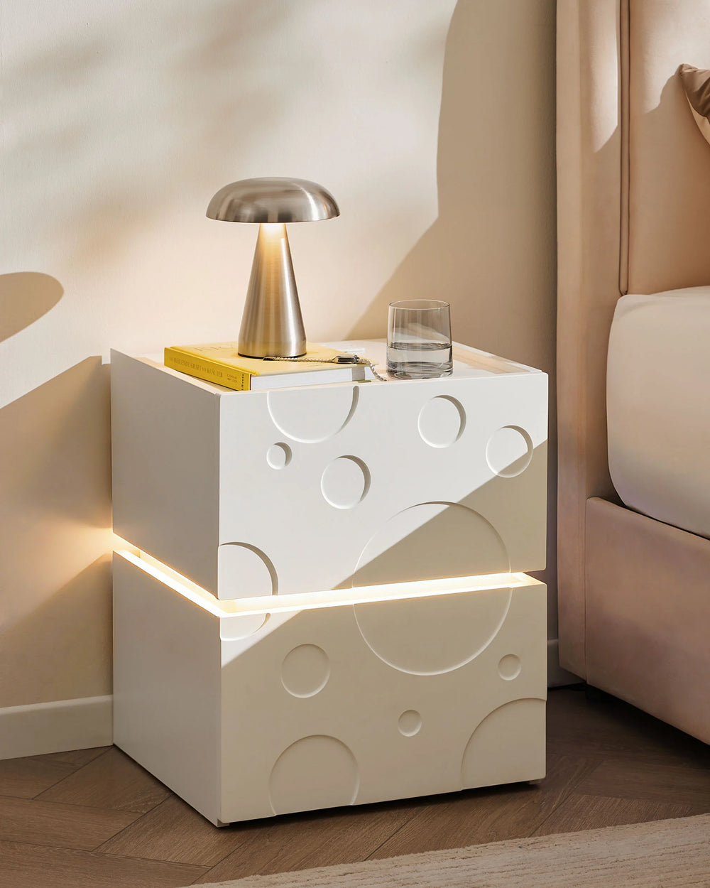 Bubbli white bedside table with warm LED light beside the bed in a cosy nighttime bedroom setting