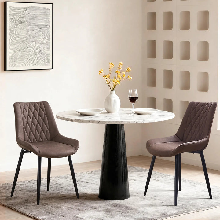 Carl Dining Chair - displaying a set of 2 brown chairs around a round dining table on a grey carpet, there are plates and a vase on the table, and a wall picture on the white wall.