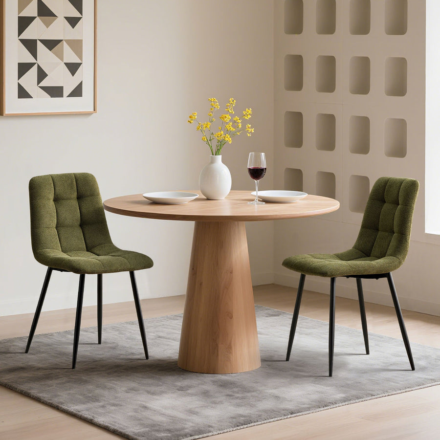 Two olive green Christie Fabric Dining Chairs beside a dining table, adding a fresh pop of colour to the dining room