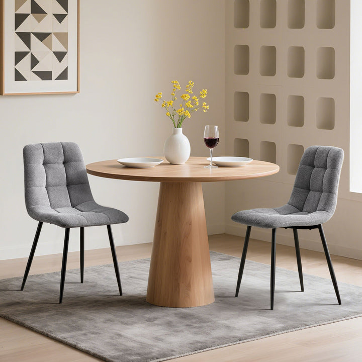Set of 2 grey Christie Fabric Dining Chairs beside a dining table.