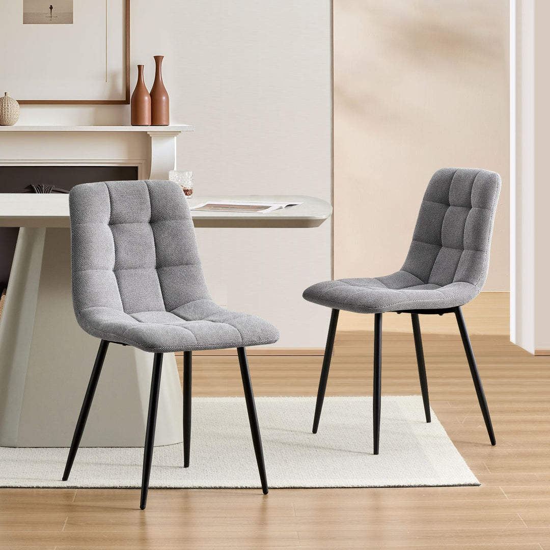 Set of 2 Grey Christie Fabric Dining Chairs placed opposite each other at a dining table.
