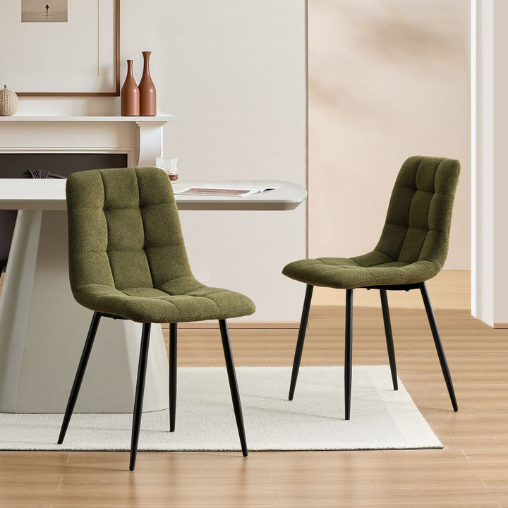 Set of 2 Olive green Christie Fabric Dining Chairs placed opposite each other at a dining table.