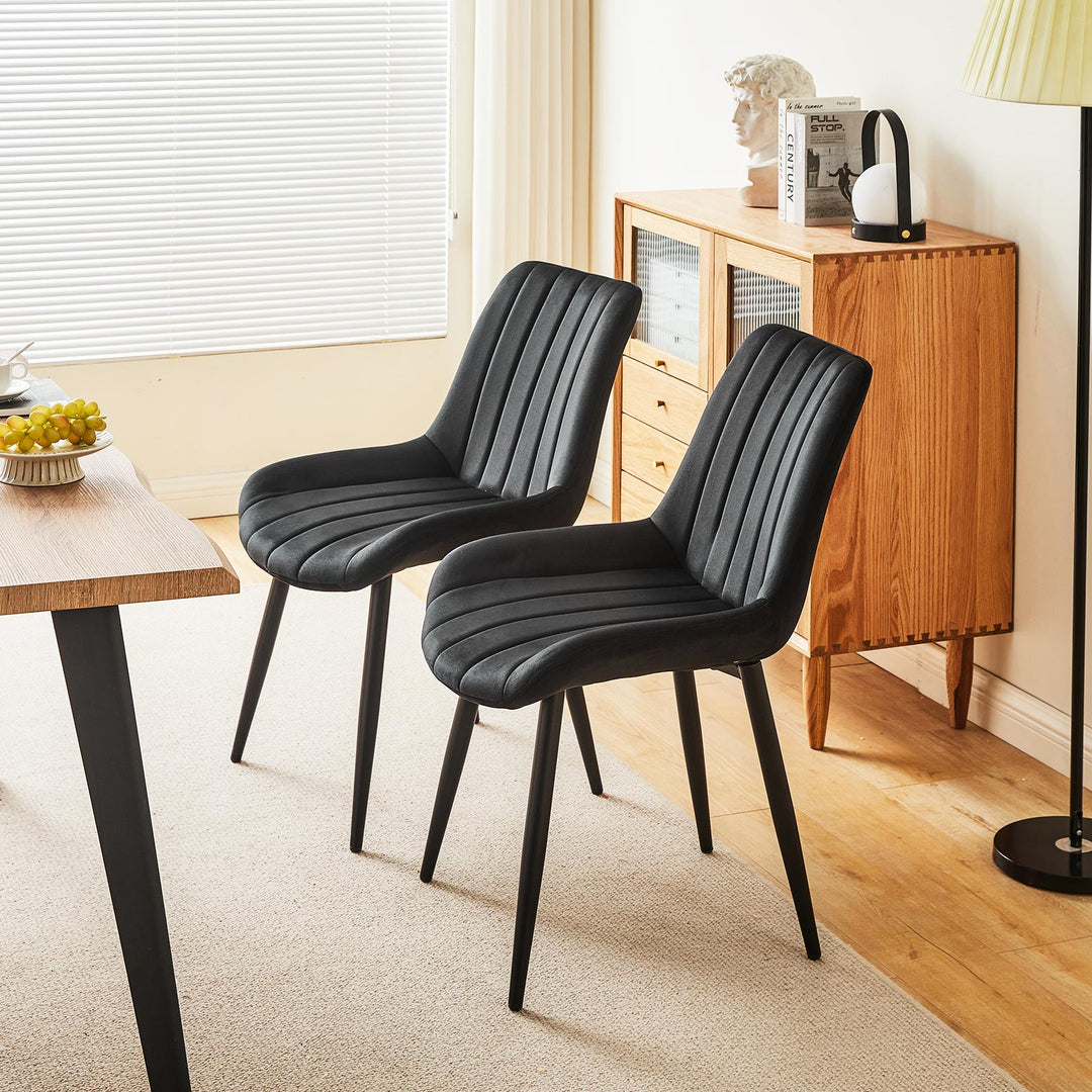 Set of 2 black velvet dining chairs with black metal legs placed on the same side of a wooden dining table in a modern dining room