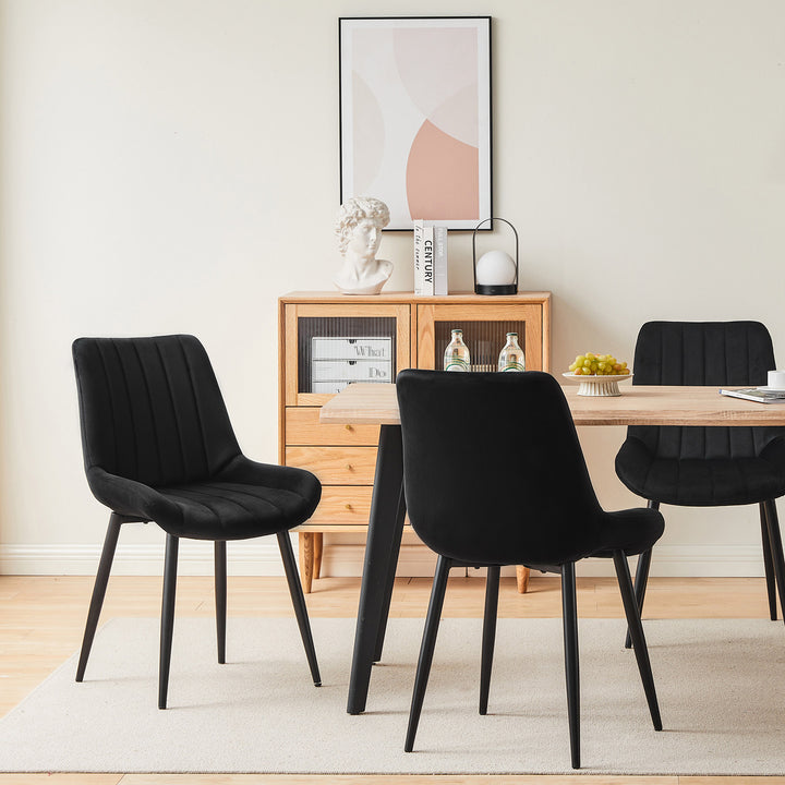 3 black velvet dining chairs around a dining table in a modern dining room, showing different angles of the chairs.