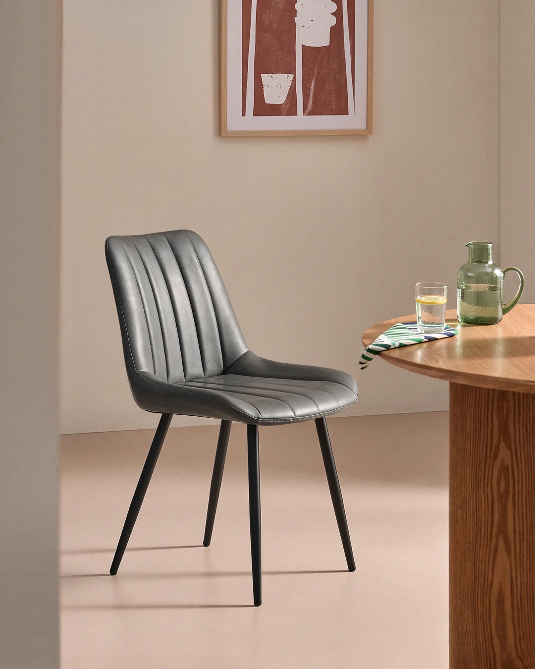 Clair grey faux leather upholstered dining chair placed in an elegant neutral dining space, perfect for modern kitchen and dining room interiors.