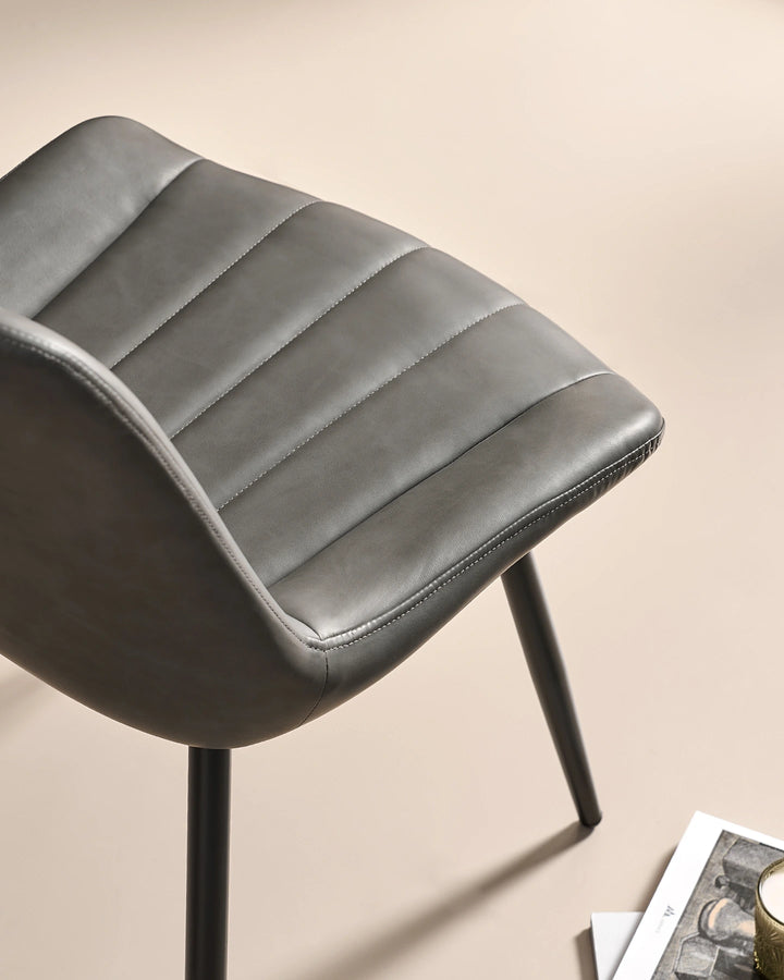 High-angle close-up of the thick padded foam seat cushion on the Clair grey faux leather dining chair, engineered for everyday dining comfort.