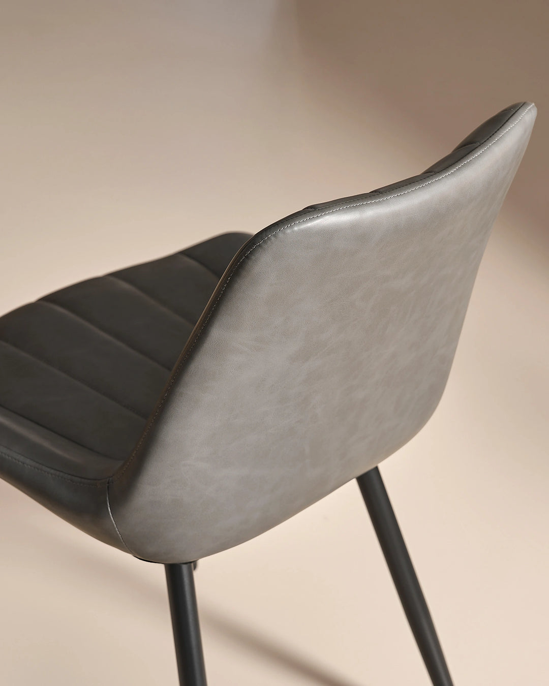 Detailed close-up showing the smooth grey faux leather finish on the reverse of the backrest and the black powder-coated metal leg fixture.