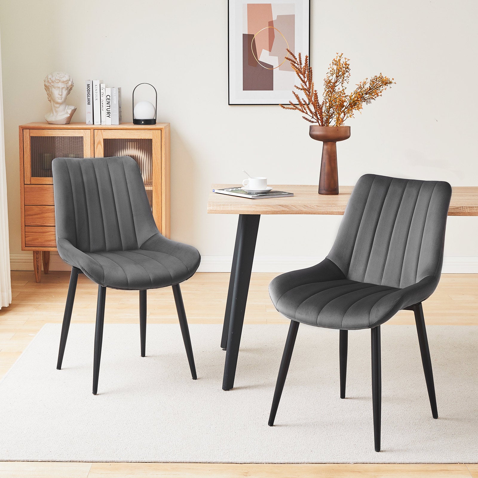 Set of 2 grey velvet dining chairs with black metal legs, placed by a wooden dining table in a modern dining room setting
