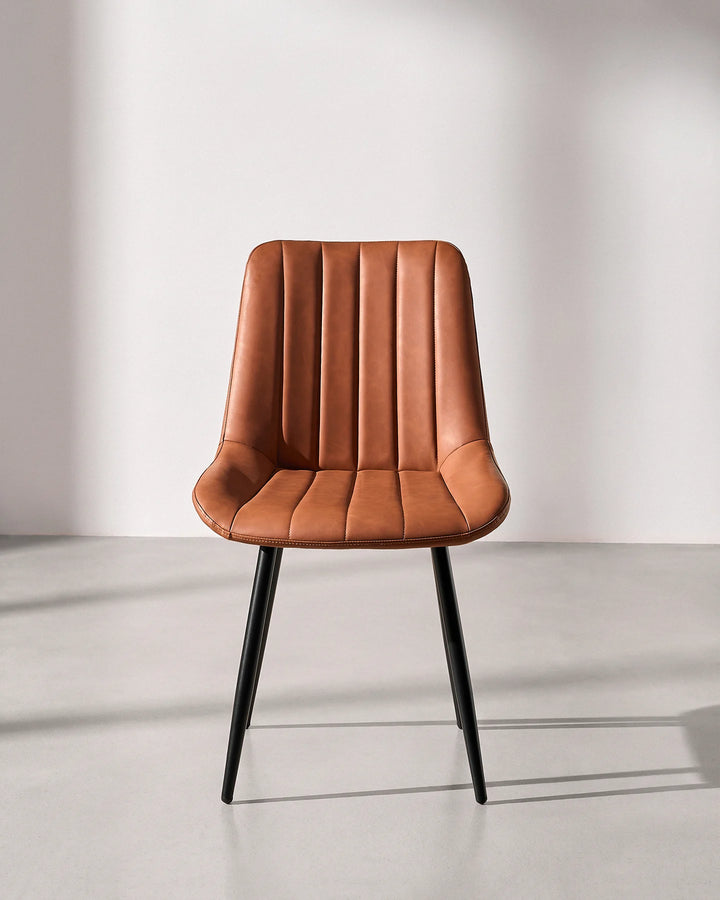 Front view of the Clair tan brown faux leather dining chair, highlighting the fluted vertical ribbed backrest and durable black metal frame.