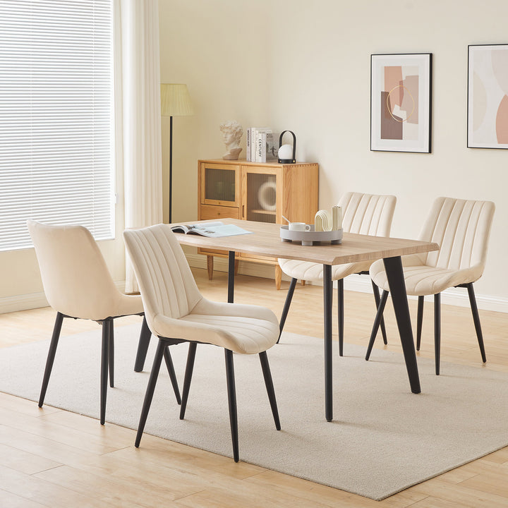 Set of 4 cream white velvet dining chairs around a dining table in a modern dining room.