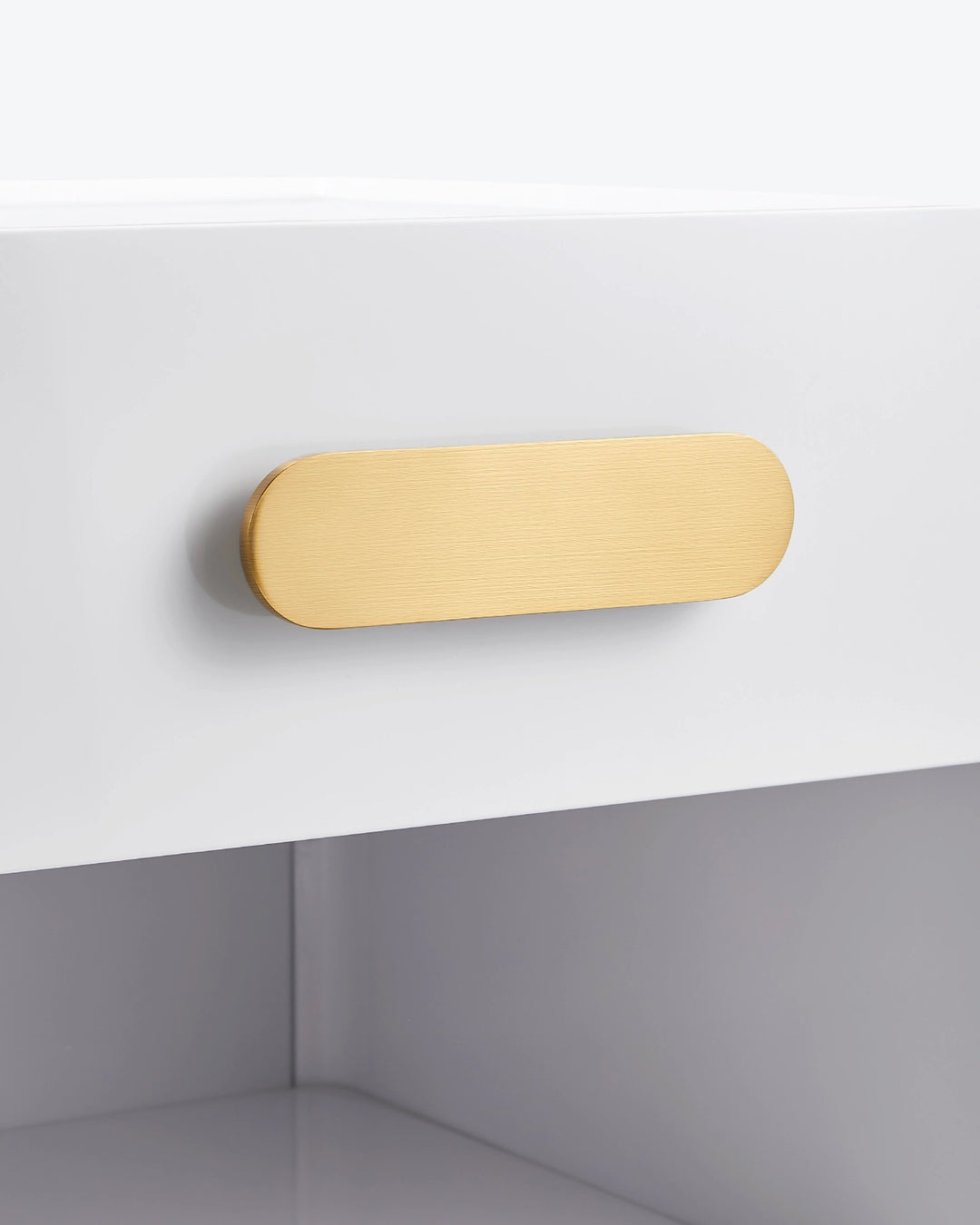 Macro close-up of the premium brushed gold handle on the white Clara bedside table drawer.