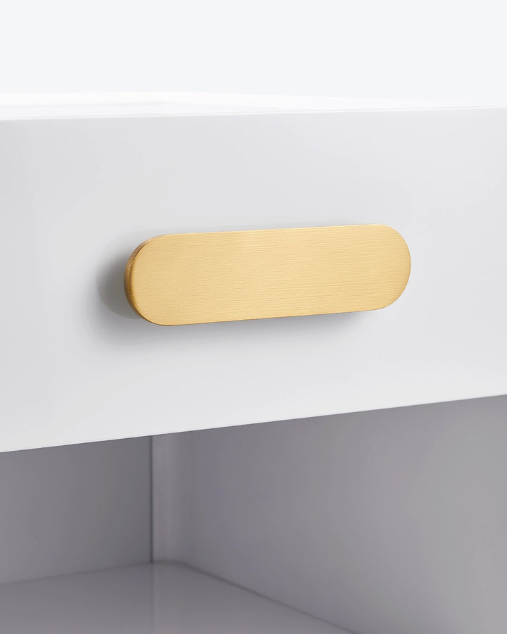 Macro close-up of the premium brushed gold handle on the white Clara bedside table drawer.