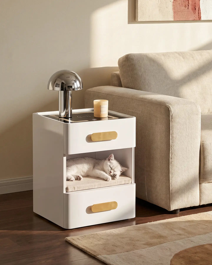 A white Clara LED bedside table with a cat sleeping comfortably in the open middle storage shelf.